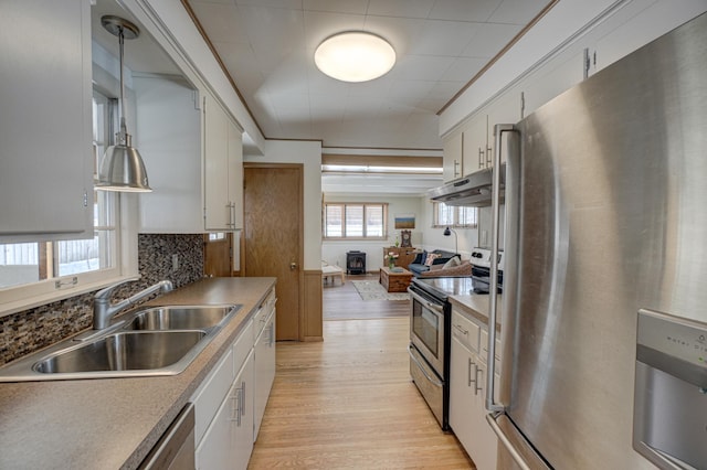 kitchen with white cabinetry, appliances with stainless steel finishes, a sink, and decorative light fixtures