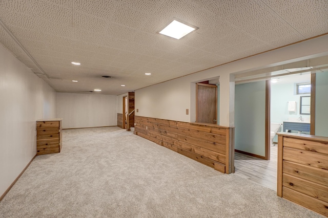 basement featuring recessed lighting, a wainscoted wall, light carpet, and wood walls