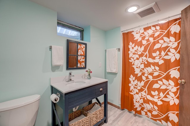 full bath featuring toilet, wood finished floors, a sink, and visible vents