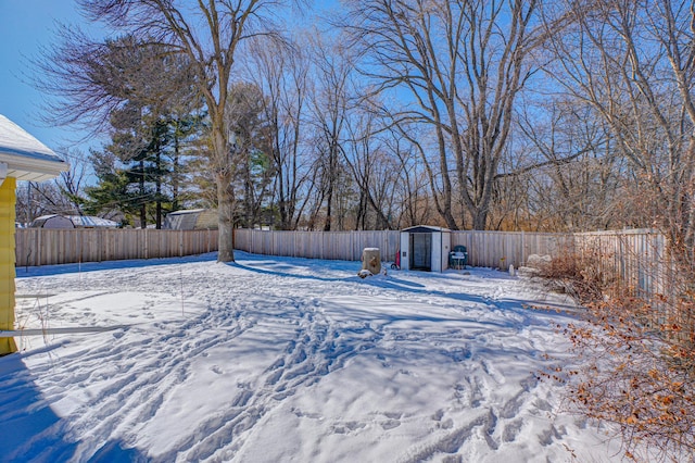 yard layered in snow with a storage shed, an outdoor structure, and a fenced backyard