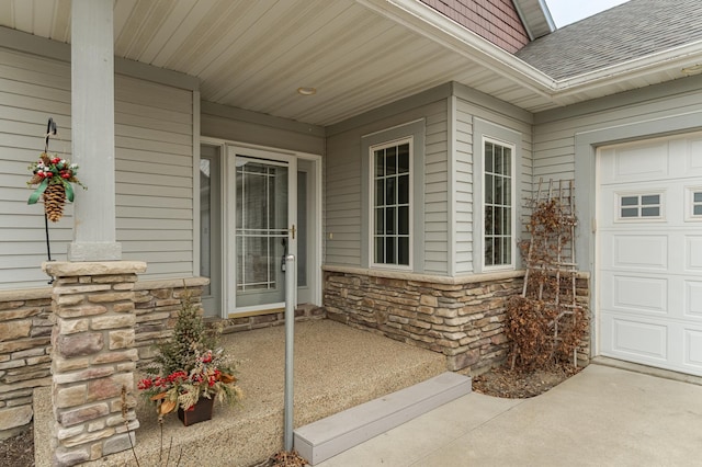 view of exterior entry featuring an attached garage, stone siding, and a shingled roof