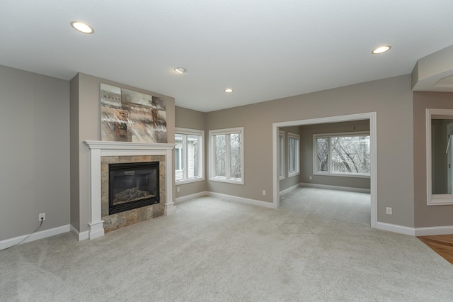 unfurnished living room with plenty of natural light, a tile fireplace, and baseboards