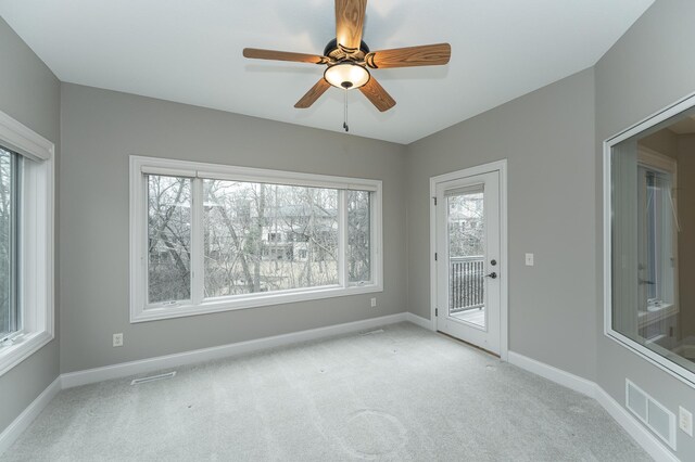 spare room featuring light colored carpet, visible vents, ceiling fan, and baseboards