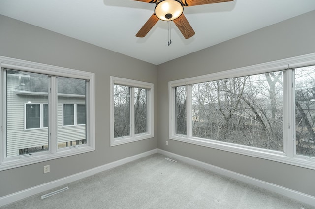 unfurnished sunroom with visible vents and a ceiling fan