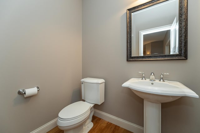 bathroom with toilet, baseboards, and wood finished floors