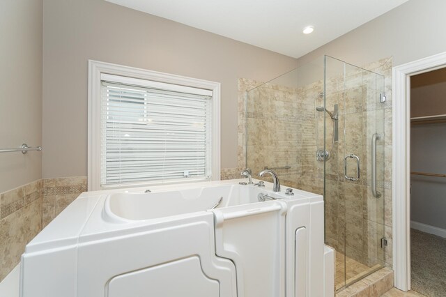 bathroom with a stall shower and a garden tub