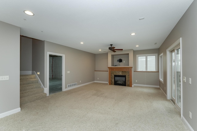 unfurnished living room featuring recessed lighting, visible vents, a tiled fireplace, carpet flooring, and stairs