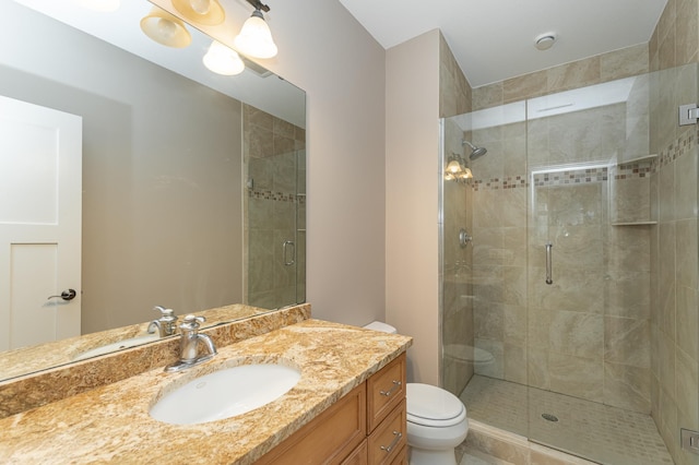 full bath featuring toilet, a shower stall, and vanity