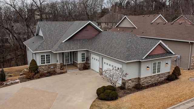 view of front facade featuring a garage, stone siding, driveway, and a shingled roof