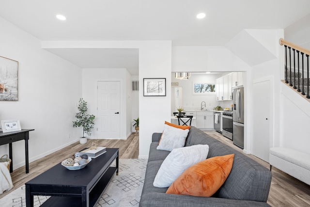 living area featuring stairs, visible vents, light wood-style flooring, and recessed lighting