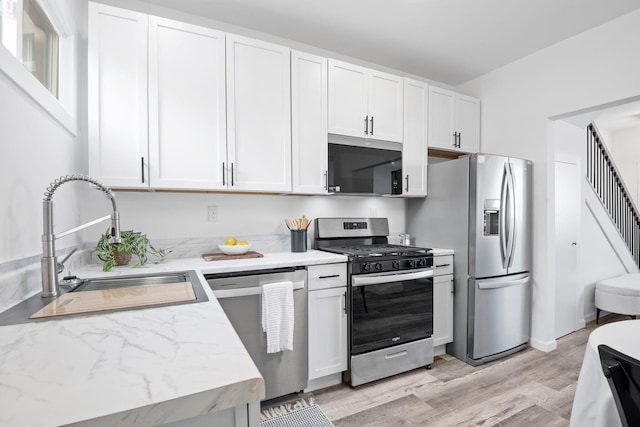 kitchen featuring appliances with stainless steel finishes, white cabinetry, and a sink