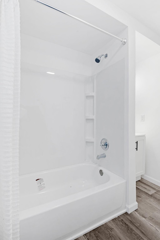 bathroom featuring shower / bathtub combination with curtain, baseboards, and wood finished floors