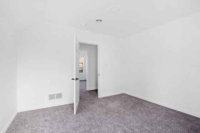 carpeted empty room with vaulted ceiling, visible vents, and baseboards