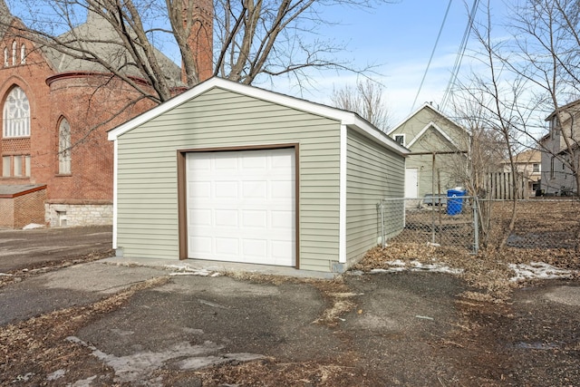 detached garage featuring driveway and fence