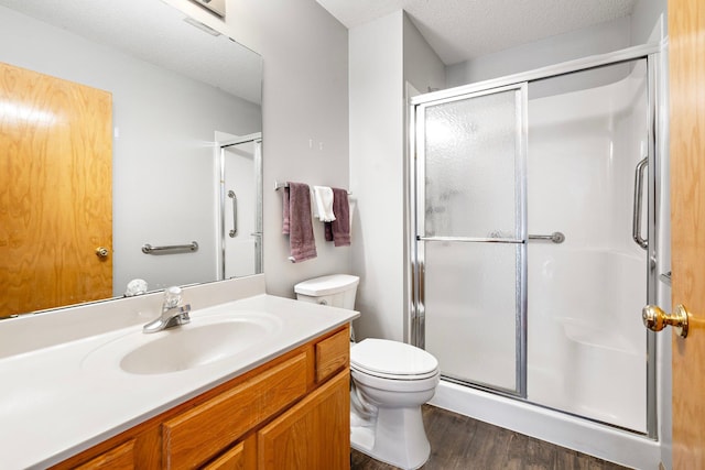 bathroom with a stall shower, vanity, toilet, and a textured ceiling