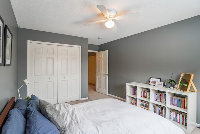 bedroom featuring a textured ceiling, light colored carpet, a ceiling fan, baseboards, and a closet