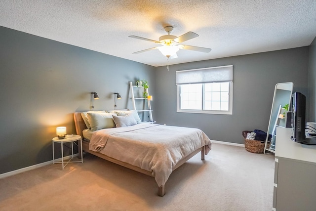 bedroom featuring baseboards, ceiling fan, a textured ceiling, and light colored carpet