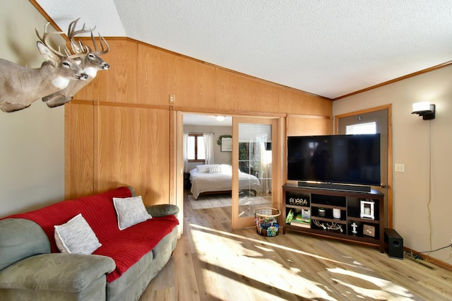 19241 Ebony Rd, Osakis, MN 56360 - living room featuring vaulted ceiling, wood finished floors, wooden walls, a textured ceiling, and crown molding