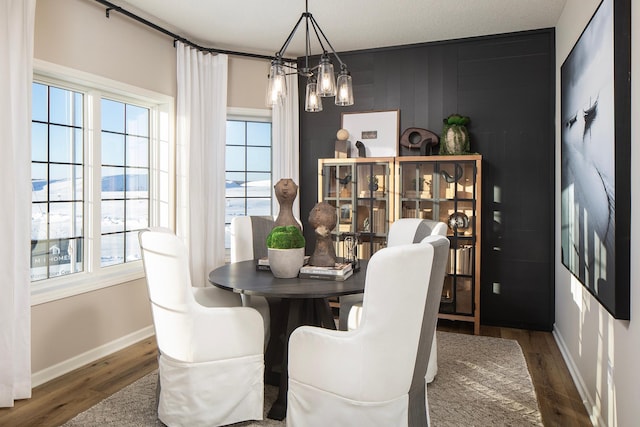 dining area featuring dark wood-style floors, plenty of natural light, a chandelier, and baseboards