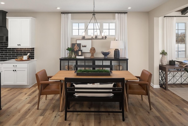 dining space featuring an inviting chandelier, baseboards, wood finished floors, and recessed lighting