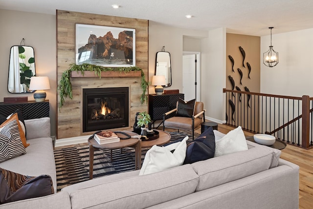 living room featuring recessed lighting, a notable chandelier, wood finished floors, a high end fireplace, and baseboards