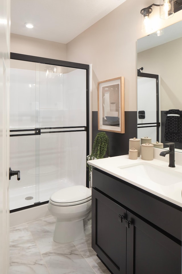 bathroom featuring a stall shower, marble finish floor, vanity, and toilet