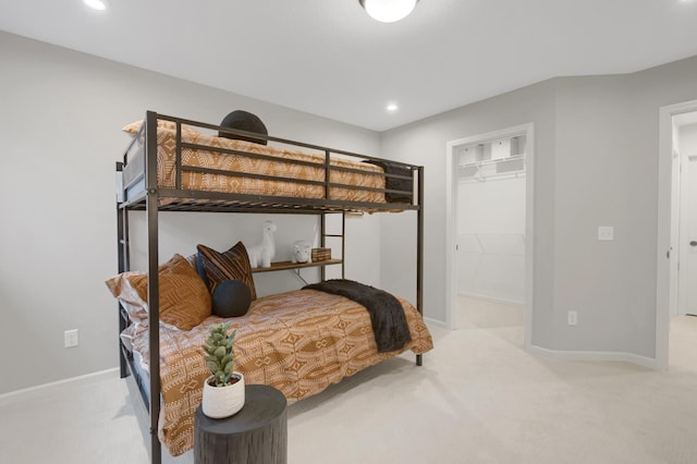 bedroom with light carpet, a spacious closet, a closet, and baseboards