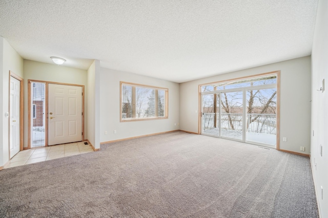 entrance foyer with light carpet, a textured ceiling, and baseboards