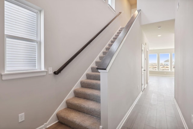 staircase featuring wood finished floors and baseboards