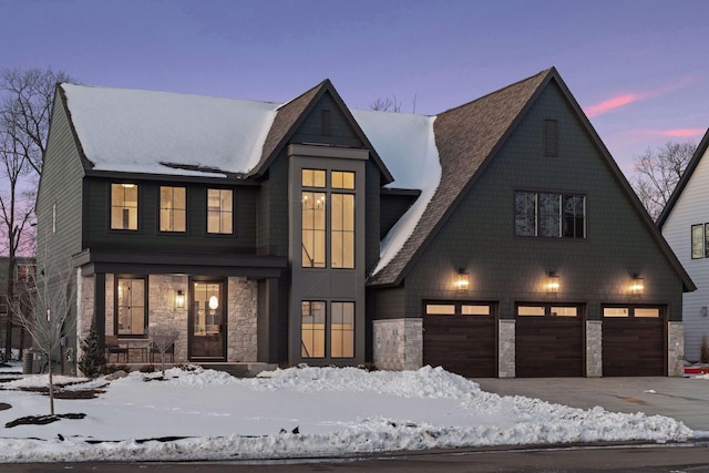 modern inspired farmhouse with stone siding, an attached garage, and driveway