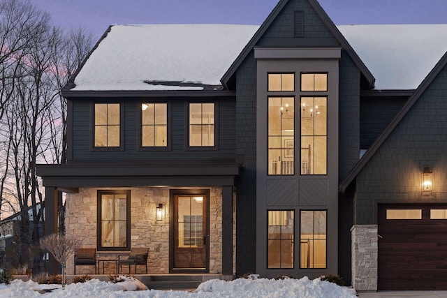 view of front of home featuring a garage, stone siding, and a porch