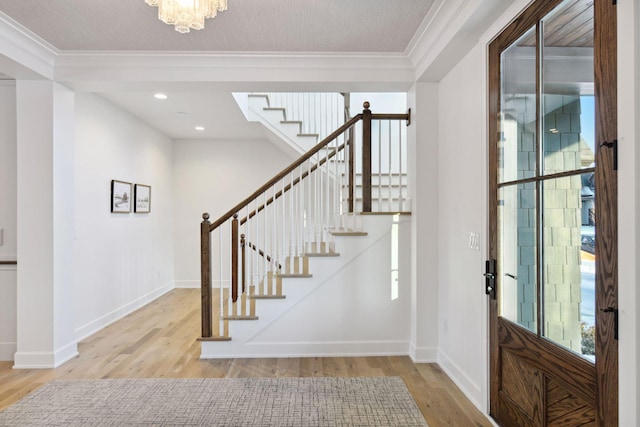 entryway featuring baseboards, stairs, ornamental molding, and wood finished floors