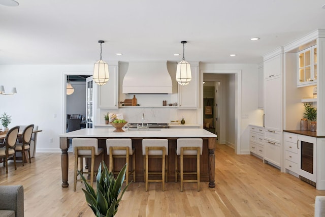 kitchen featuring premium range hood, a breakfast bar, a sink, and white cabinetry