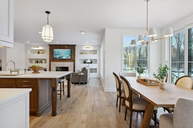 dining room featuring a chandelier, recessed lighting, a large fireplace, baseboards, and light wood-style floors