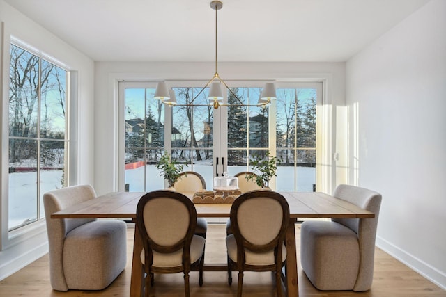 dining room featuring light wood-style floors, baseboards, and a chandelier