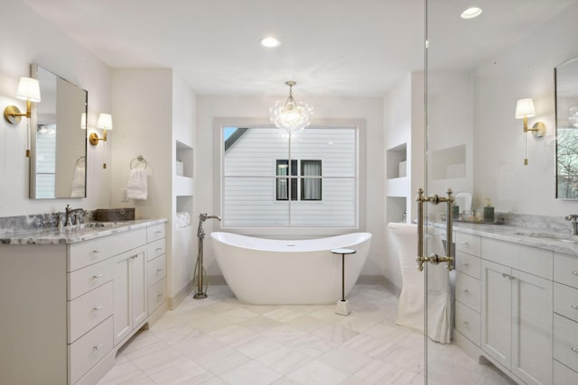 bathroom with a freestanding bath, two vanities, and a sink