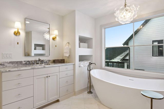 full bathroom featuring a freestanding tub, tile patterned floors, a chandelier, and vanity