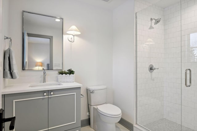 bathroom with toilet, a stall shower, baseboards, and vanity