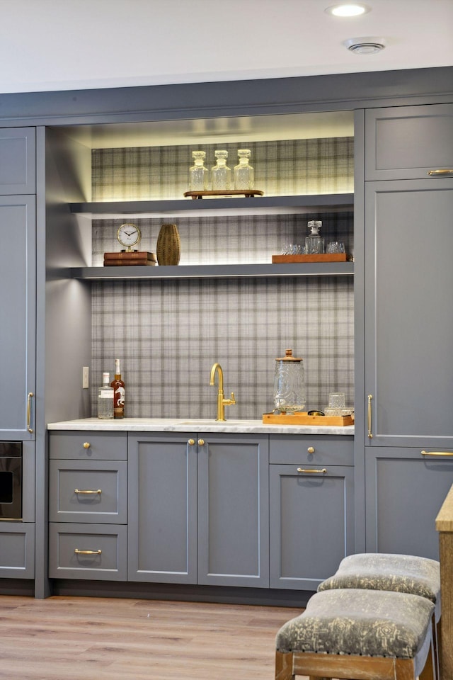 bar with wood finished floors and backsplash