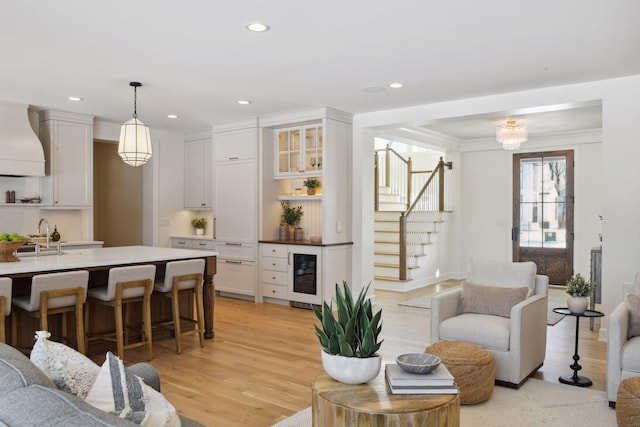 living area with light wood-type flooring, wine cooler, recessed lighting, and stairs