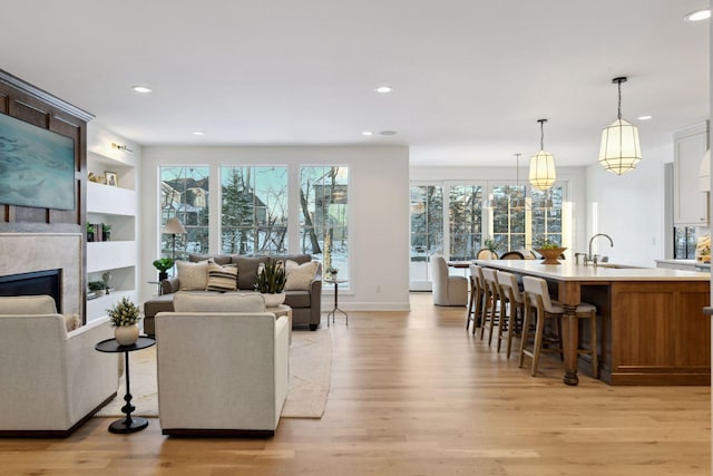 living area featuring baseboards, light wood-style flooring, built in shelves, a fireplace, and recessed lighting