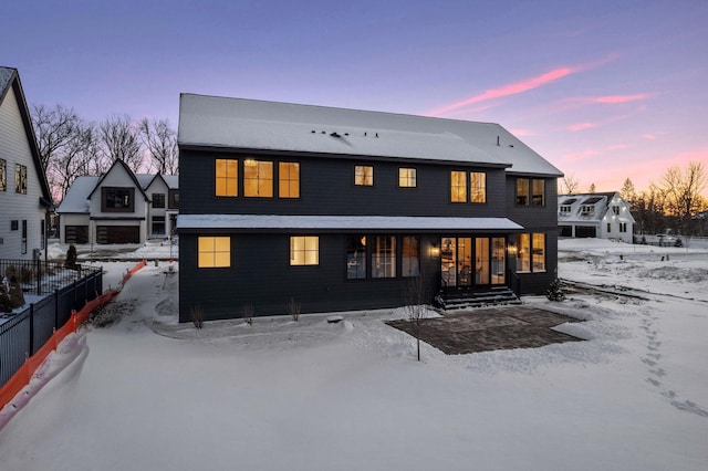 snow covered house featuring fence