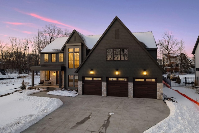 view of front of property featuring stone siding, an attached garage, concrete driveway, and fence