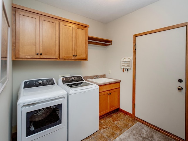 clothes washing area with cabinet space, a sink, washer and clothes dryer, and baseboards