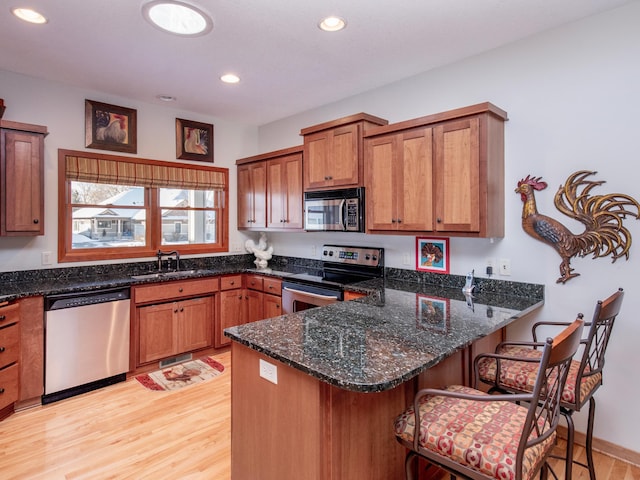 kitchen with a peninsula, appliances with stainless steel finishes, and dark stone countertops