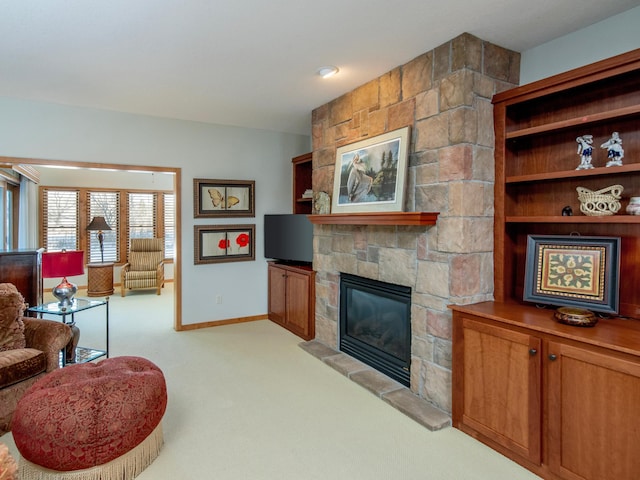 living room featuring baseboards, a stone fireplace, and light colored carpet