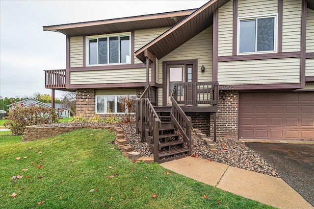 view of front facade with a garage, a front yard, brick siding, and driveway