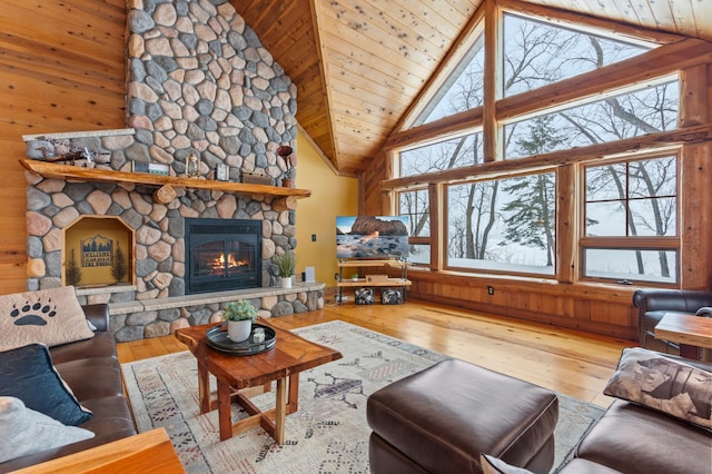 living room with high vaulted ceiling, wooden walls, a fireplace, wood ceiling, and light wood-type flooring