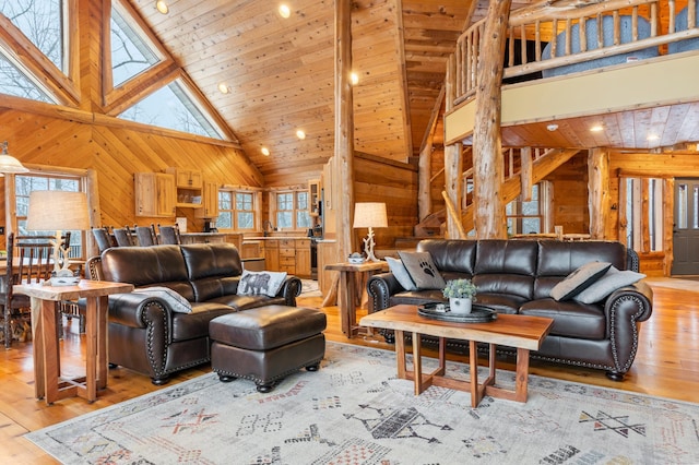 living area featuring light wood-style flooring, wood walls, high vaulted ceiling, and wooden ceiling