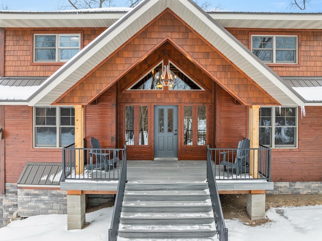 snow covered property entrance featuring a porch and metal roof